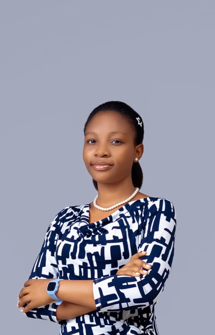Glory Akanbi, arms folded, in a navy and white patterned top, photographed against a pale studio background.