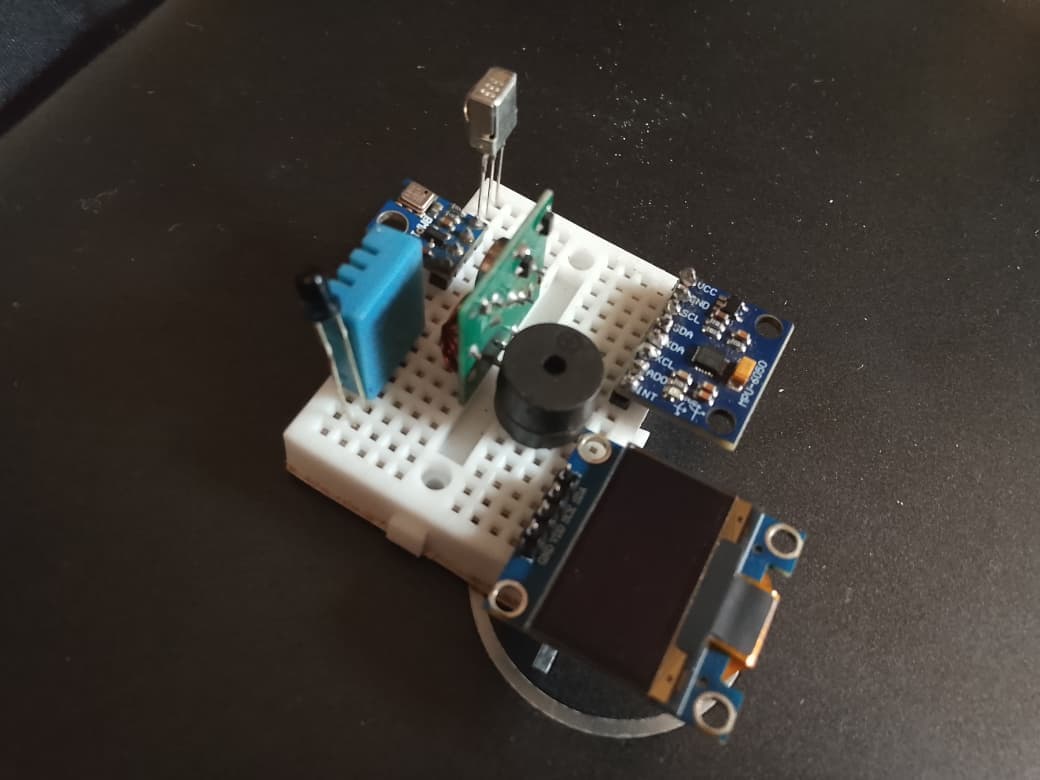Close view of the TremorSense sensor stack on a mini breadboard: an MPU-6050 inertial measurement unit, a DHT11 temperature and humidity sensor, a piezo buzzer and a small OLED display.